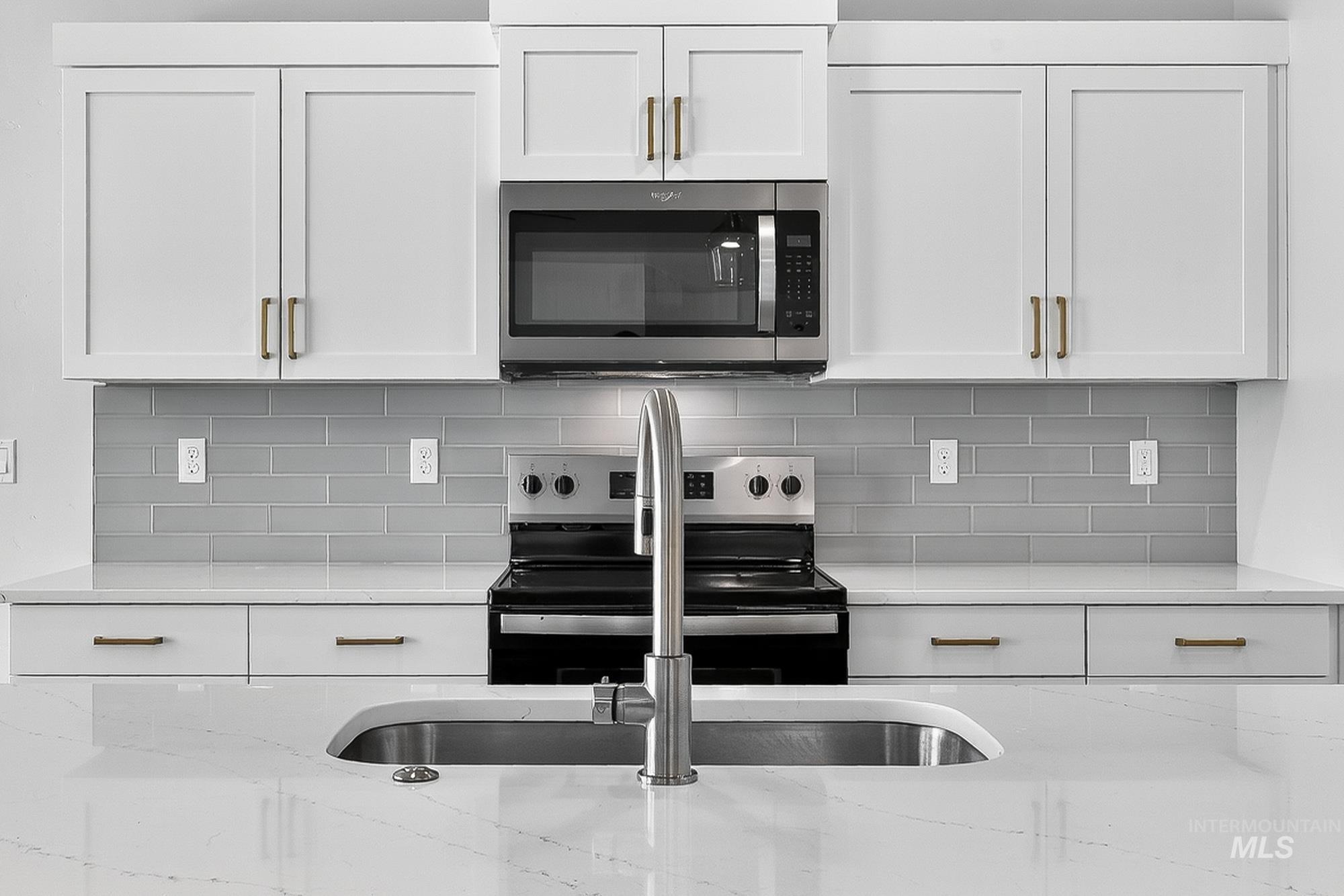 1158 Velvet Loop Wilder, ID 83676 - Photo 12 of 34 Kitchen with appliances with stainless steel finishes, white cabinetry, light stone countertops, and backsplash