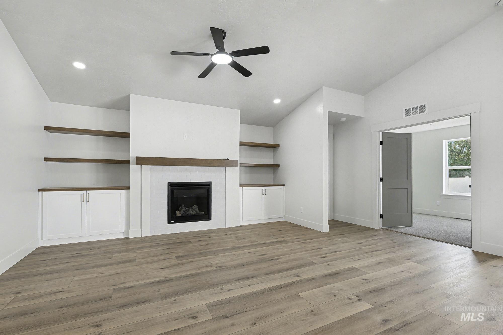 1158 Velvet Loop Wilder, ID 83676 - Photo 4 of 34 Unfurnished living room featuring a glass covered fireplace, light wood finished floors, a ceiling fan, lofted ceiling, and recessed lighting