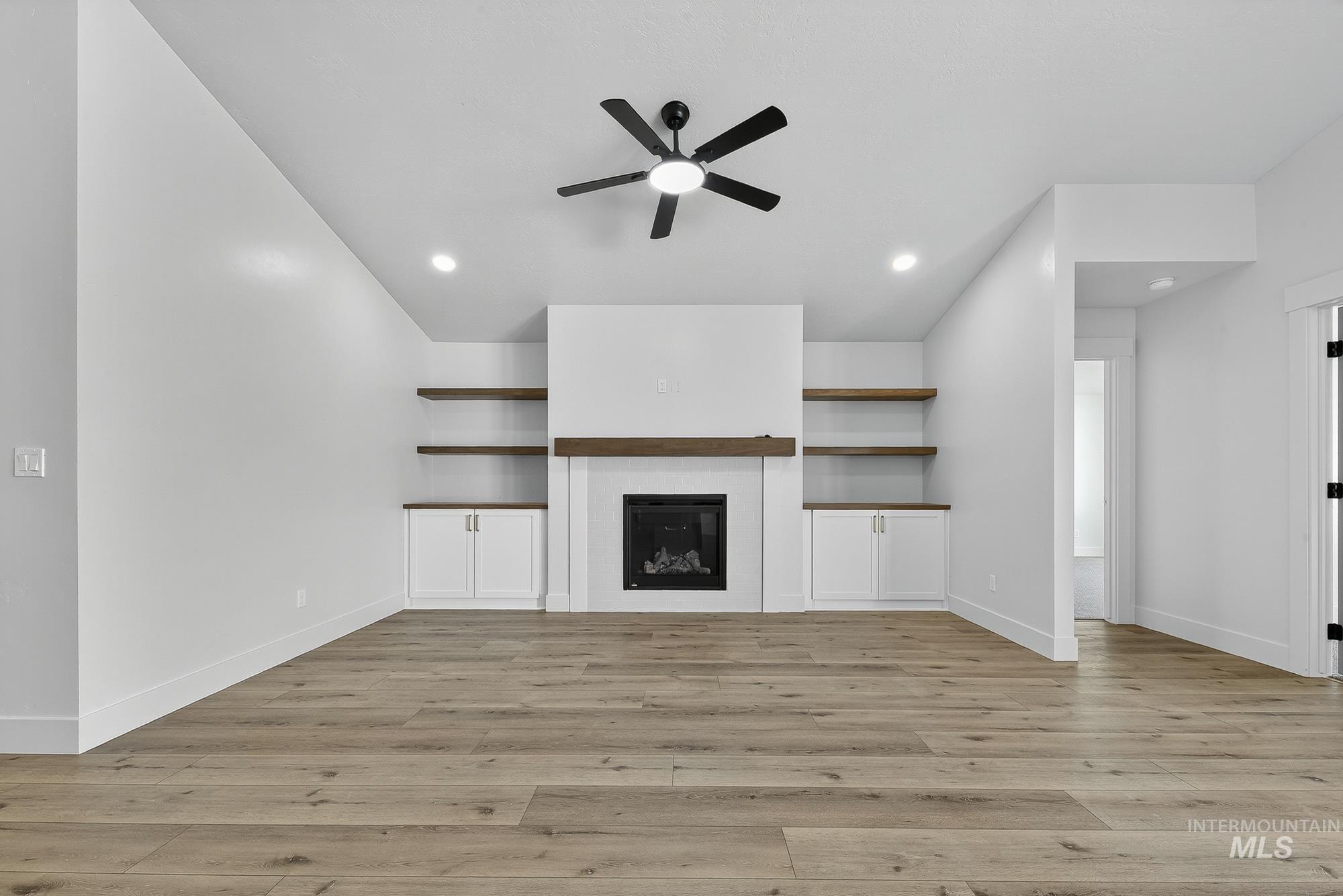 1158 Velvet Loop Wilder, ID 83676 - Photo 5 of 34 Unfurnished living room featuring a glass covered fireplace, light wood finished floors, and ceiling fan