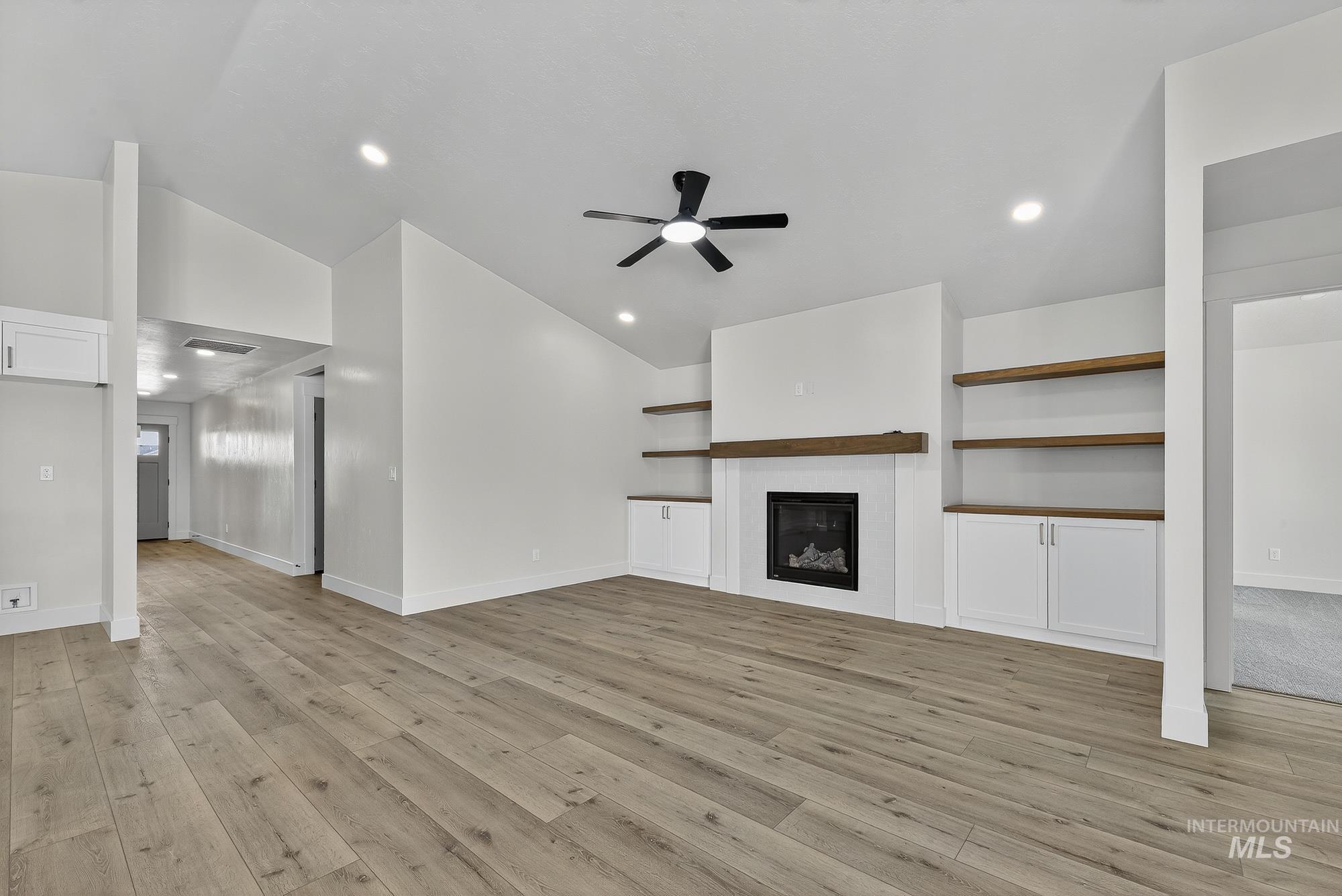 1158 Velvet Loop Wilder, ID 83676 - Photo 6 of 34 Unfurnished living room with a glass covered fireplace, ceiling fan, light wood-type flooring, lofted ceiling, and recessed lighting