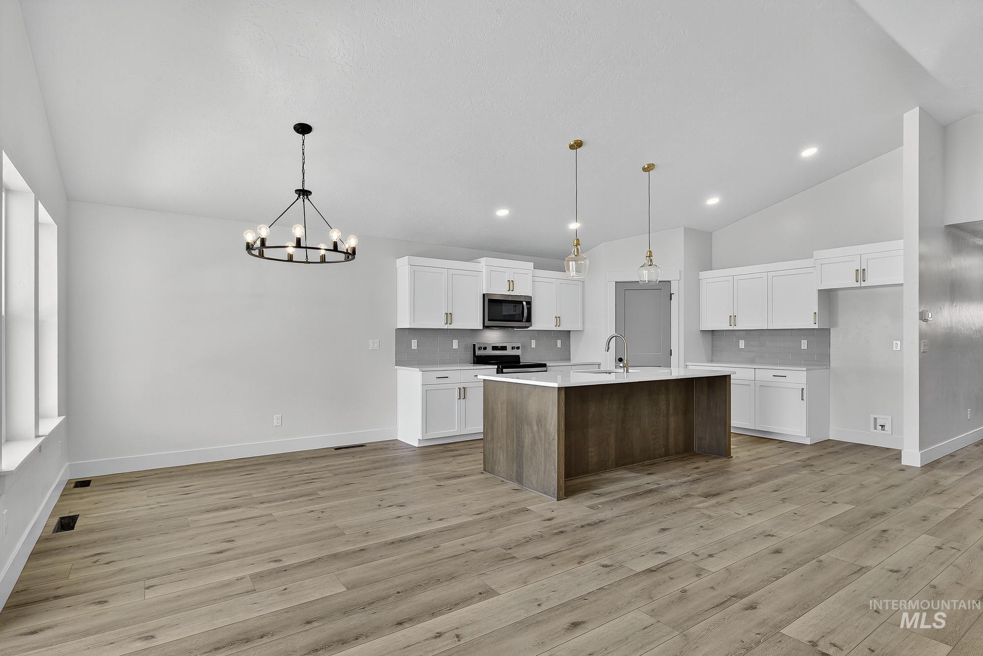 1158 Velvet Loop Wilder, ID 83676 - Photo 7 of 34 Kitchen featuring white cabinets, tasteful backsplash, hanging light fixtures, a center island with sink, and a chandelier
