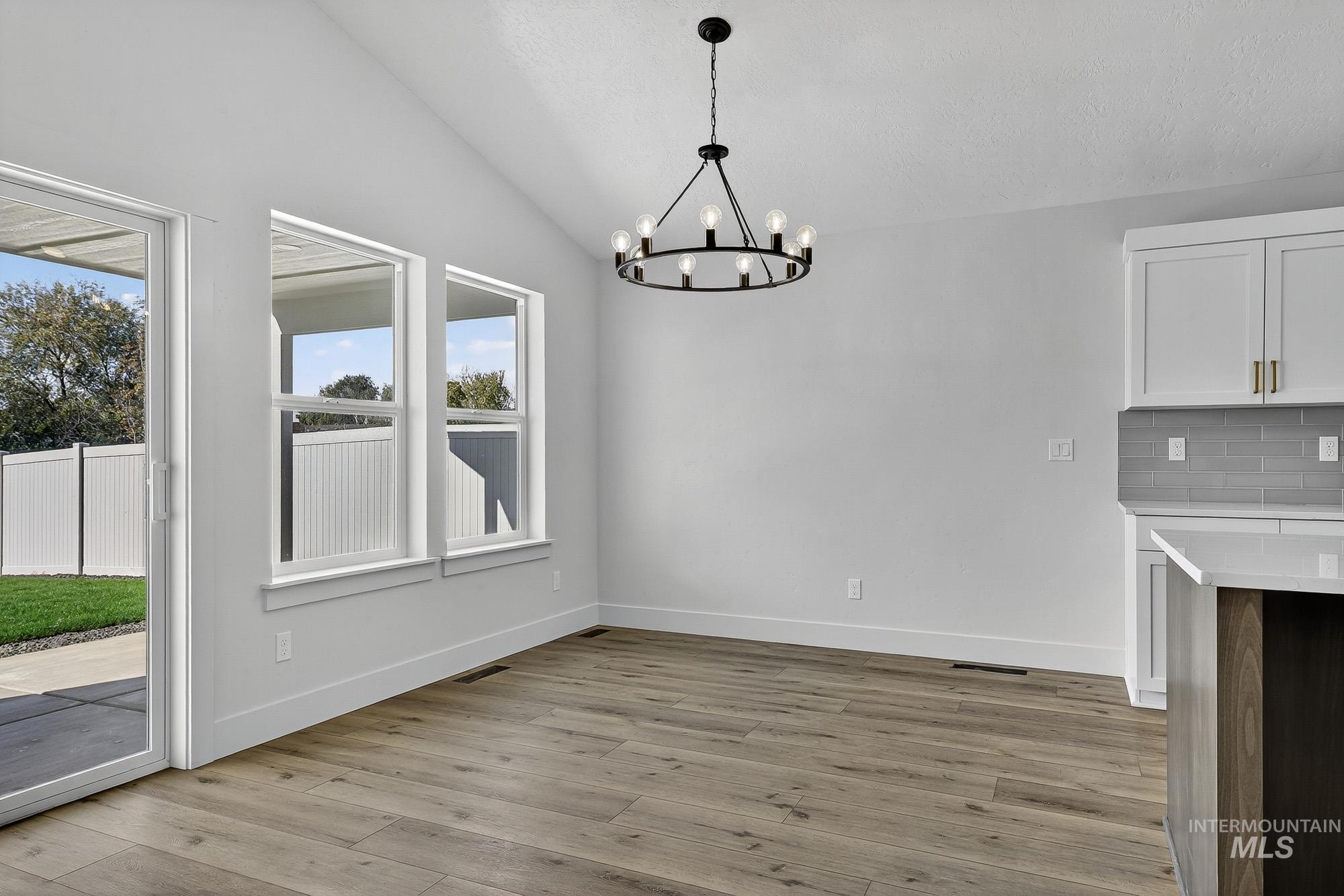1158 Velvet Loop Wilder, ID 83676 - Photo 8 of 34 Unfurnished dining area featuring lofted ceiling, light wood-style floors, and a chandelier