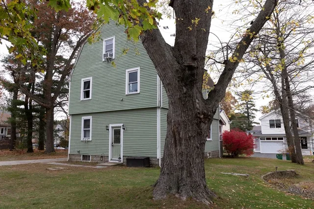 a front view of a house with a large tree and a yard