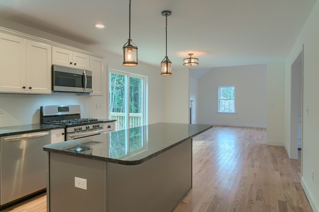 73 Meadow Road Townsend, MA 01469 - Photo 4 of 25 a kitchen with stainless steel appliances granite countertop a sink a stove top oven a refrigerator with grey cabinets and wooden floor