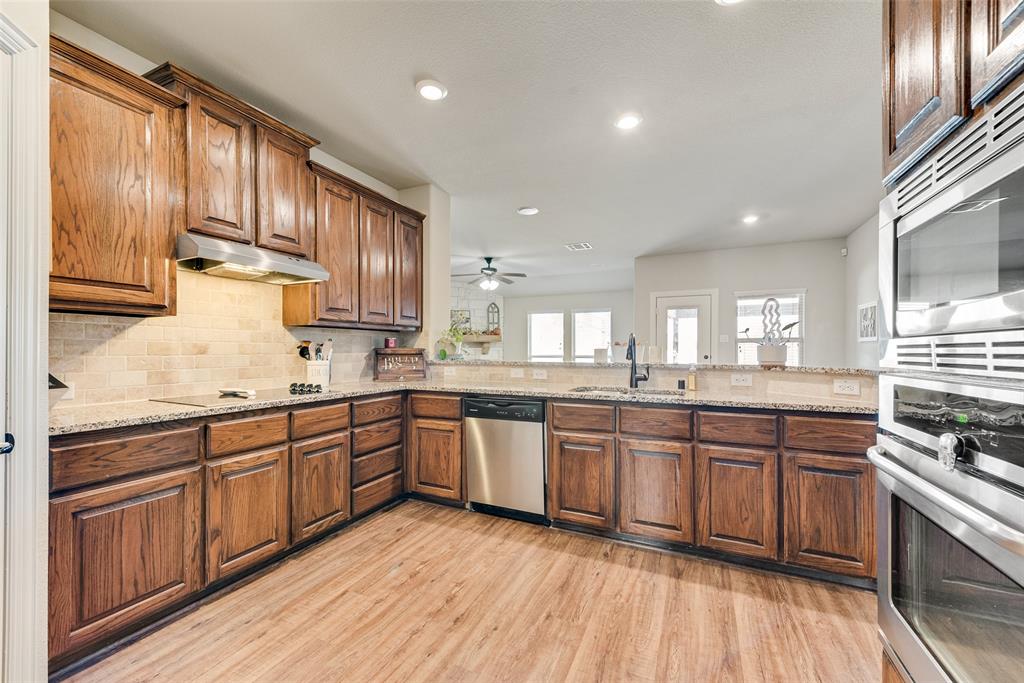 343 Amber Lane Nevada, TX 75173 - Photo 12 of 33 a kitchen with stainless steel appliances granite countertop wooden cabinets a sink dishwasher a stove and a refrigerator with wooden floor