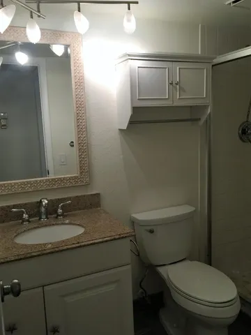 a bathroom with a toilet sink vanity and mirror