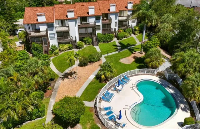 an aerial view of a house with outdoor space and trees all around