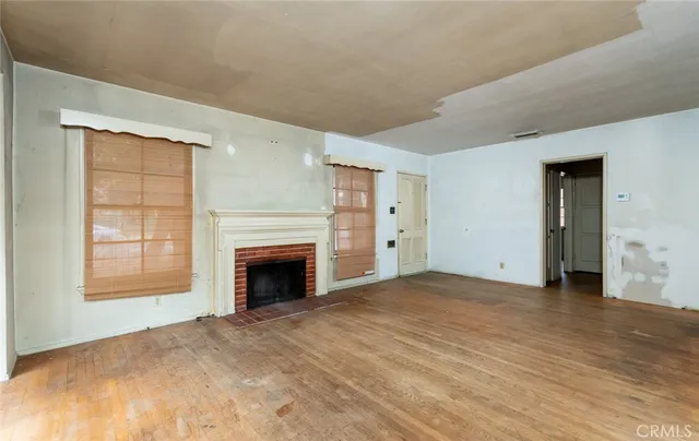 an empty room with windows and fireplace