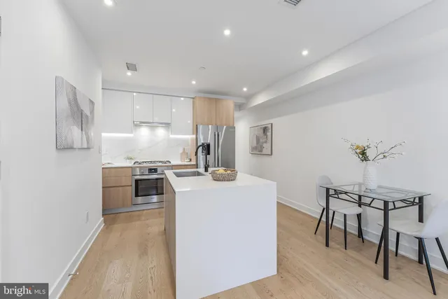 a kitchen with kitchen island a stove a table and chairs in it