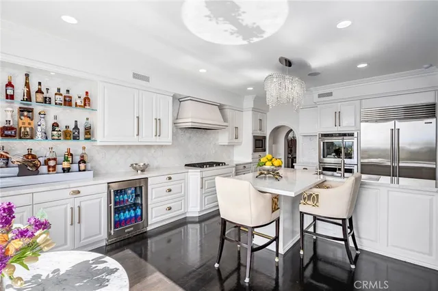 a kitchen with stainless steel appliances kitchen island granite countertop a table chairs sink and cabinets