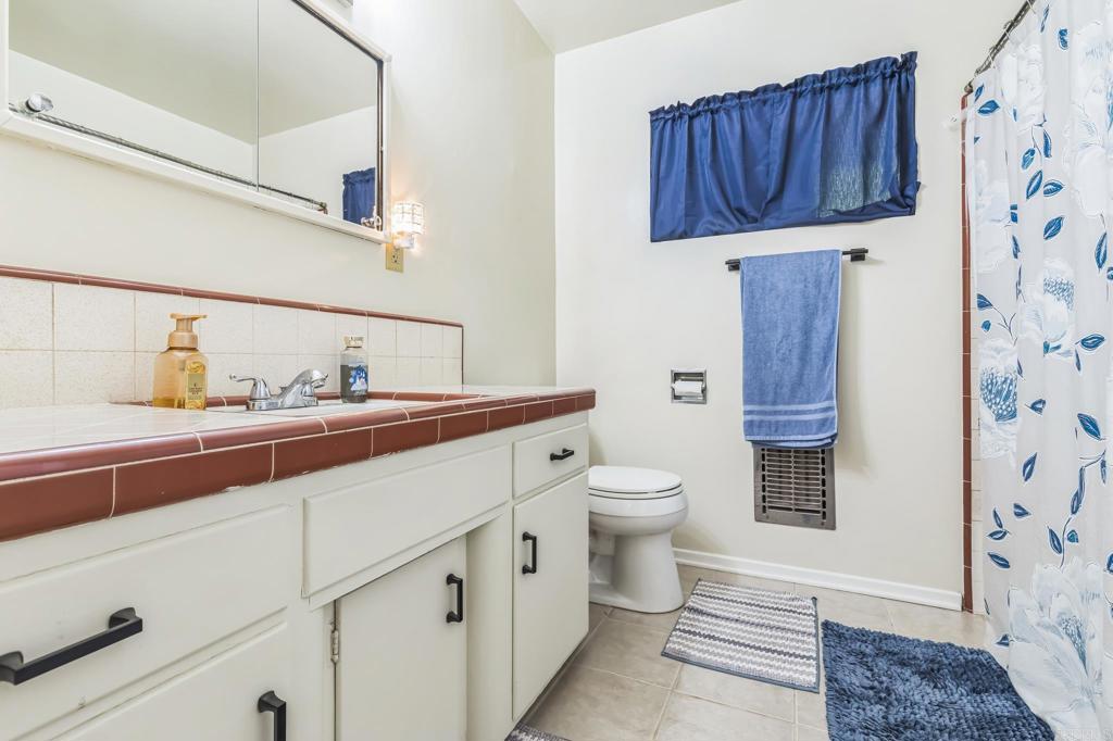 1350 Coy Court El Cajon, CA 92021 - Photo 28 of 30 a bathroom with a sink a toilet and shower curtain