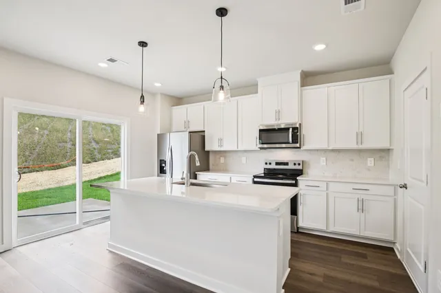 a kitchen with stainless steel appliances granite countertop a sink a stove a refrigerator a center island with wooden floor and cabinets