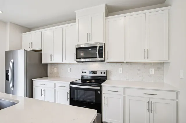 a kitchen with white cabinets and stainless steel appliances