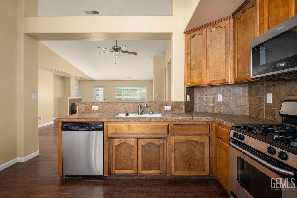 Undisclosed Address Bakersfield, CA 93312 - Photo 16 of 21 a kitchen with stainless steel appliances a sink a stove a microwave and wooden cabinets
