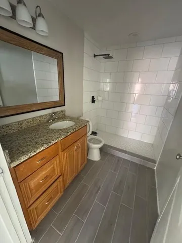 a bathroom with a granite countertop sink a toilet and shower