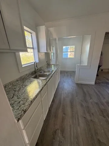 a large kitchen with kitchen island granite countertop wooden floors a sink and a window