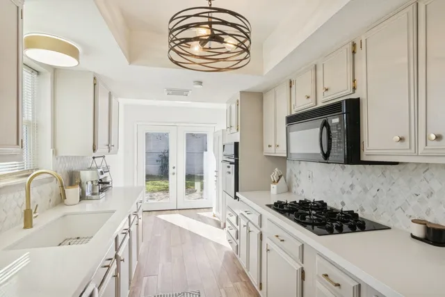 a kitchen with stainless steel appliances a stove a sink and a white cabinets