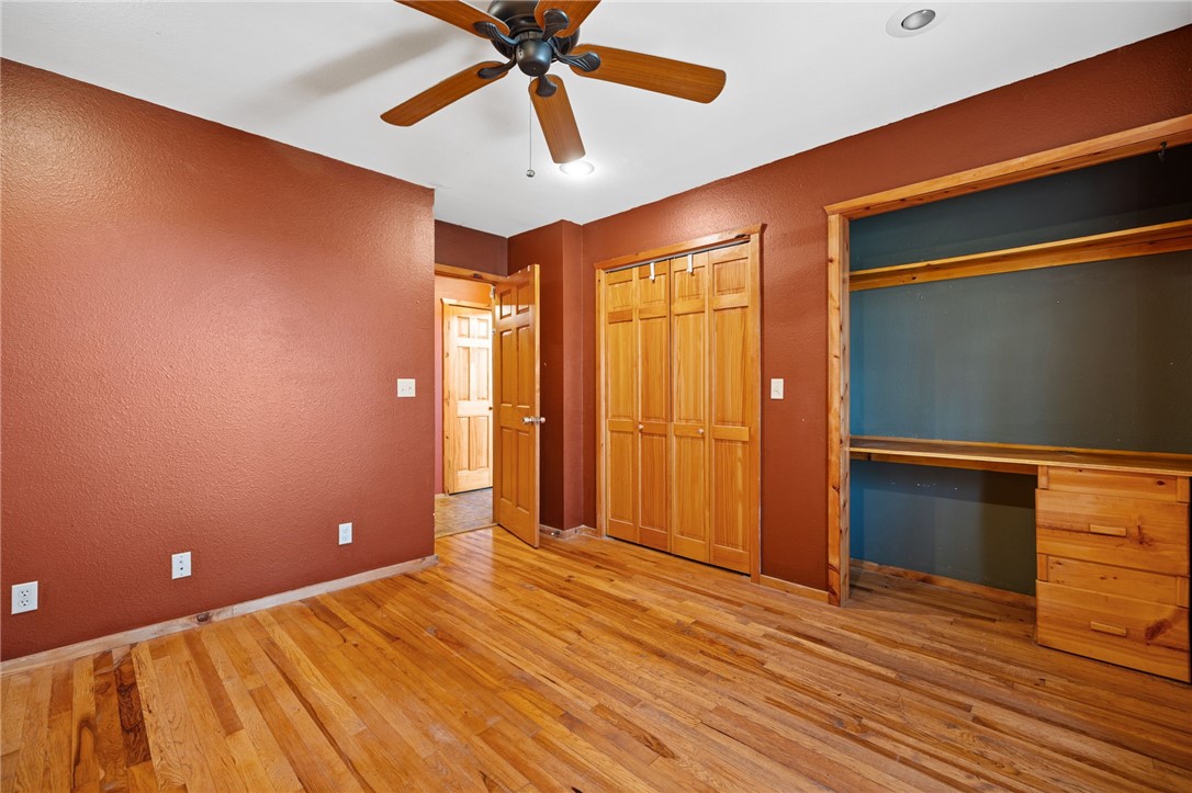 10557 North Devils Den Road Winslow, AR 72959 - Photo 23 of 60 Unfurnished bedroom featuring built in study area, multiple closets, light wood-type flooring, a ceiling fan, and a textured wall