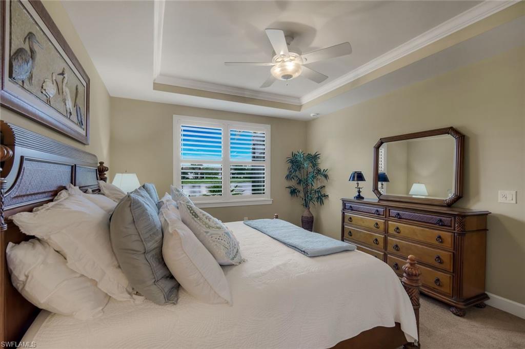 10820 Rutherford Road Fort Myers, FL 33913 - Photo 23 of 42 Tray ceiling, ceiling fan with light fixture, window with plantation shutters, wood-finish headboard, and wood-finish dresser
