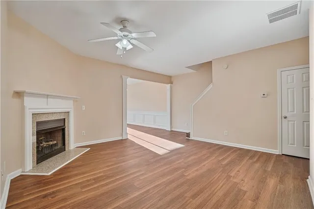 a view of an empty room with wooden floor and a fireplace