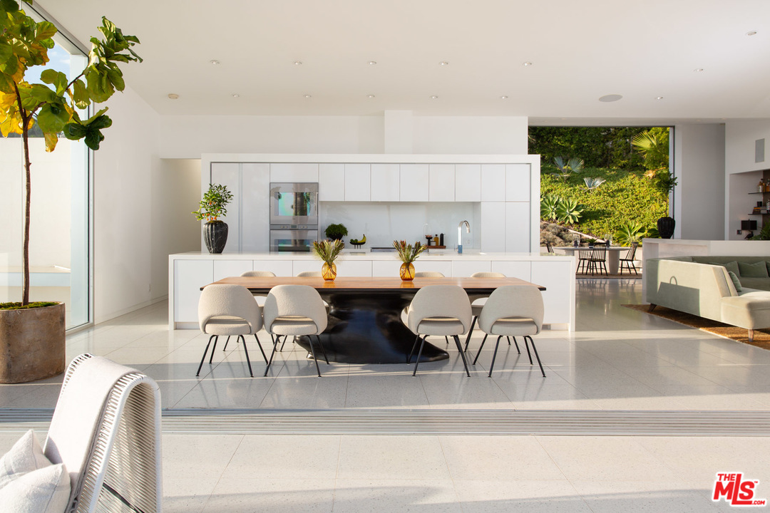213 Pintoresca Drive Pacific Palisades, CA 90272 - Photo 9 of 23 a view of a dining room with furniture a potted plant and a floor to ceiling window