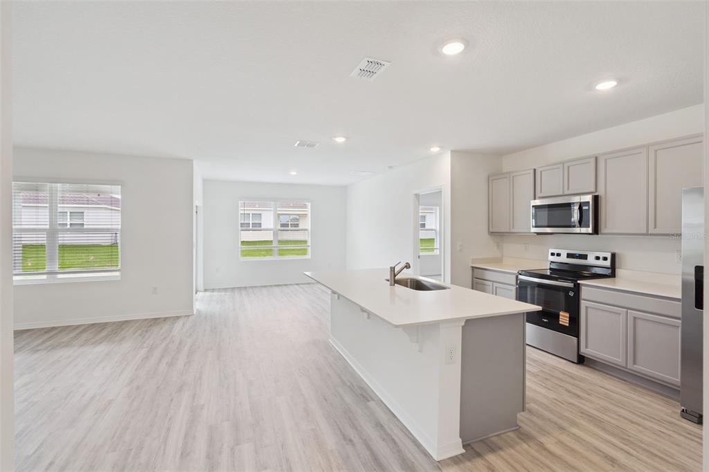 5131 Orchard Oriole Loop Bartow, FL 33830 - Photo 6 of 17 a kitchen with stainless steel appliances a stove a sink a refrigerator white cabinets and wooden floor