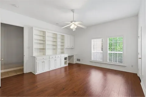 an empty room with chandelier fan and windows