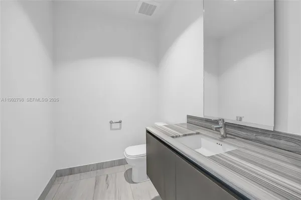 a bathroom with a granite countertop sink a toilet and a mirror