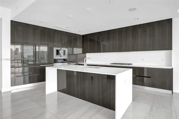 a kitchen with kitchen island granite countertop wooden cabinets a refrigerator and a sink