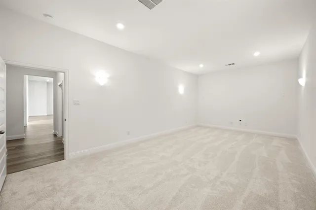 an empty room with chandelier fan and windows