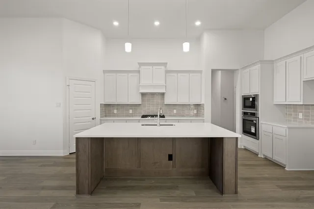 a large kitchen with kitchen island a sink white cabinets and stainless steel appliances