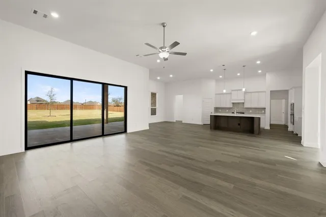 a view of an empty room with a kitchen and a window