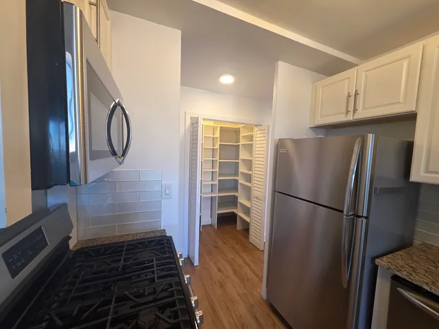 a kitchen with a refrigerator a stove and wooden floor