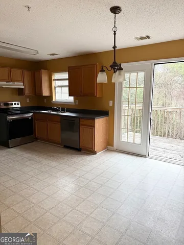 a large kitchen with granite countertop a stove a sink dishwasher a dining table and chairs with wooden floor