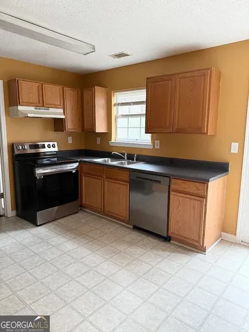 a kitchen with stainless steel appliances granite countertop a stove a sink and a refrigerator