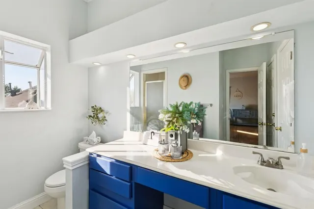 a bathroom with a granite countertop sink and a mirror with toilet