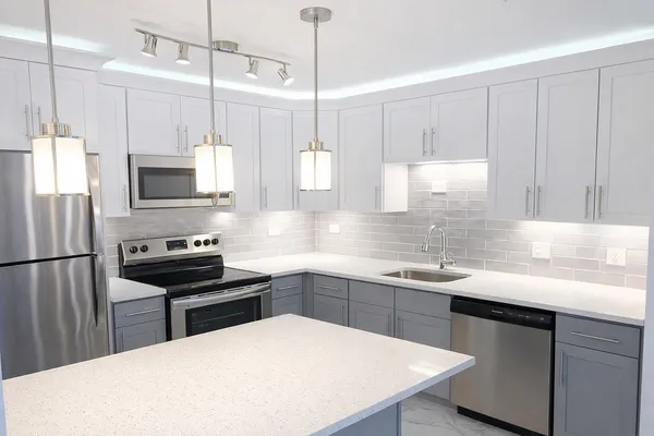 a kitchen with stainless steel appliances a stove a sink a microwave a center island and cabinets
