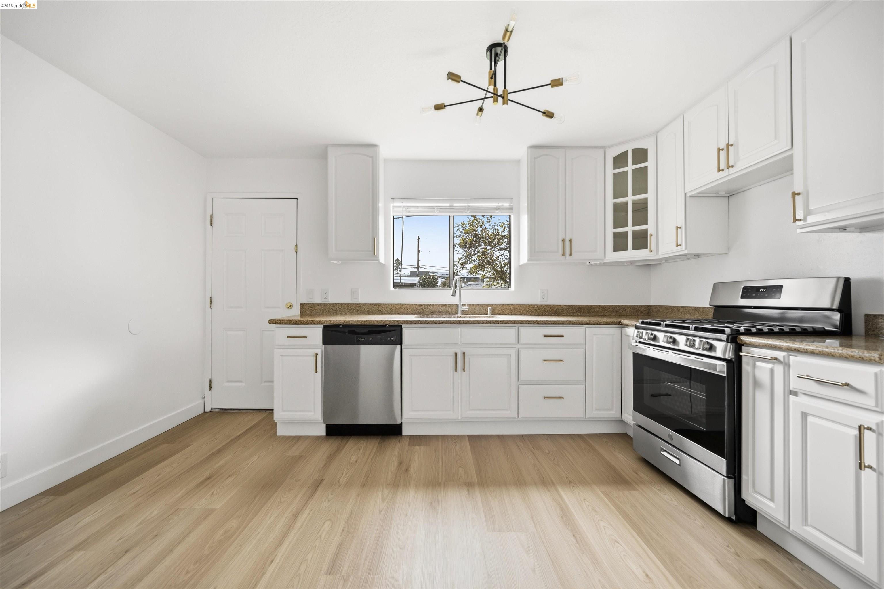 10933 Julius Street, Unit D Oakland, CA 94605 - Photo 8 of 28 a kitchen with a sink cabinets stainless steel appliances and a window