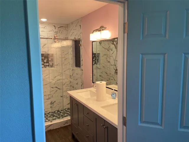 a bathroom with a granite countertop sink a mirror and a shower