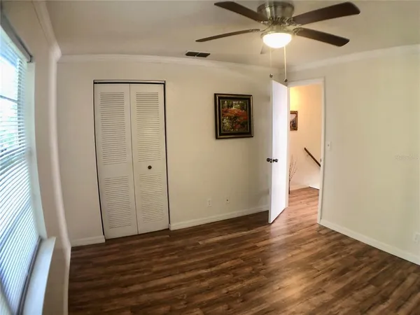 an empty room with wooden floor fan and windows