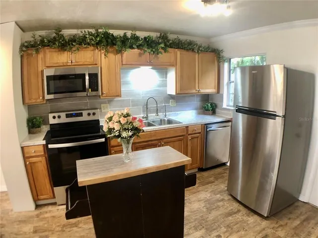 a kitchen with stainless steel appliances a refrigerator a stove a sink cabinets and a dining table