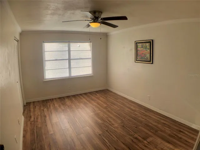 a view of an empty room with a window and wooden floor