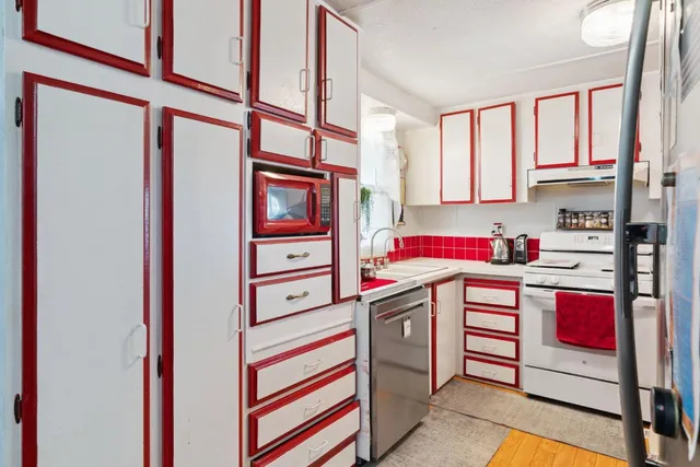 a utility room with stainless steel appliances wooden floor and window