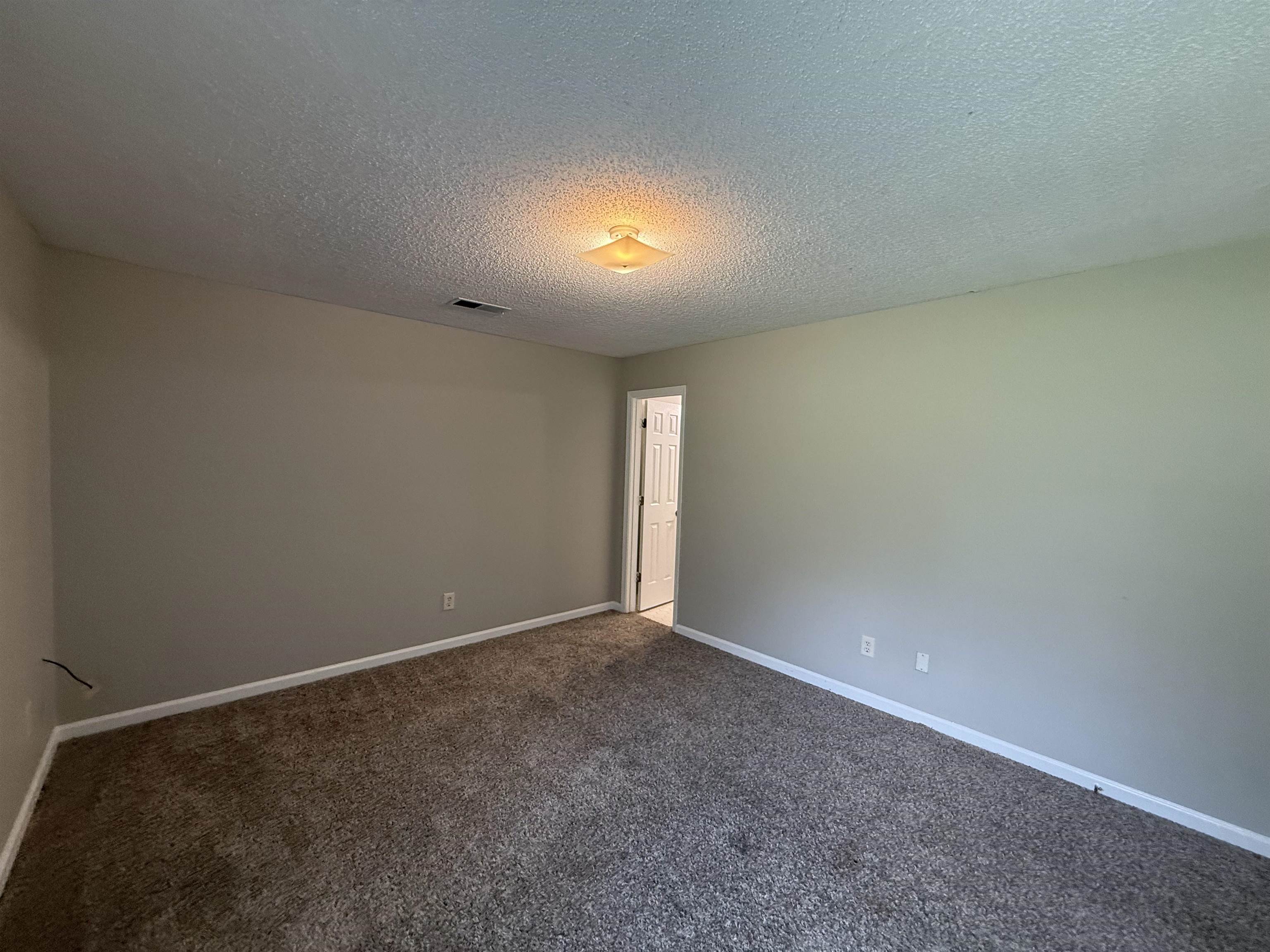 6420 Saginaw Road Memphis, TN 38134 - Photo 26 of 38 Spacious room featuring neutral painted walls, textured ceiling, and low-pile carpet flooring