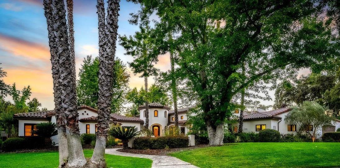 a front view of a house with a garden and tree