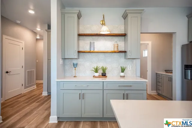 a kitchen with kitchen island white cabinets and refrigerator