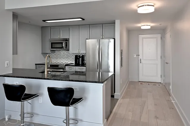 a kitchen with stainless steel appliances granite countertop a refrigerator and a stove top oven