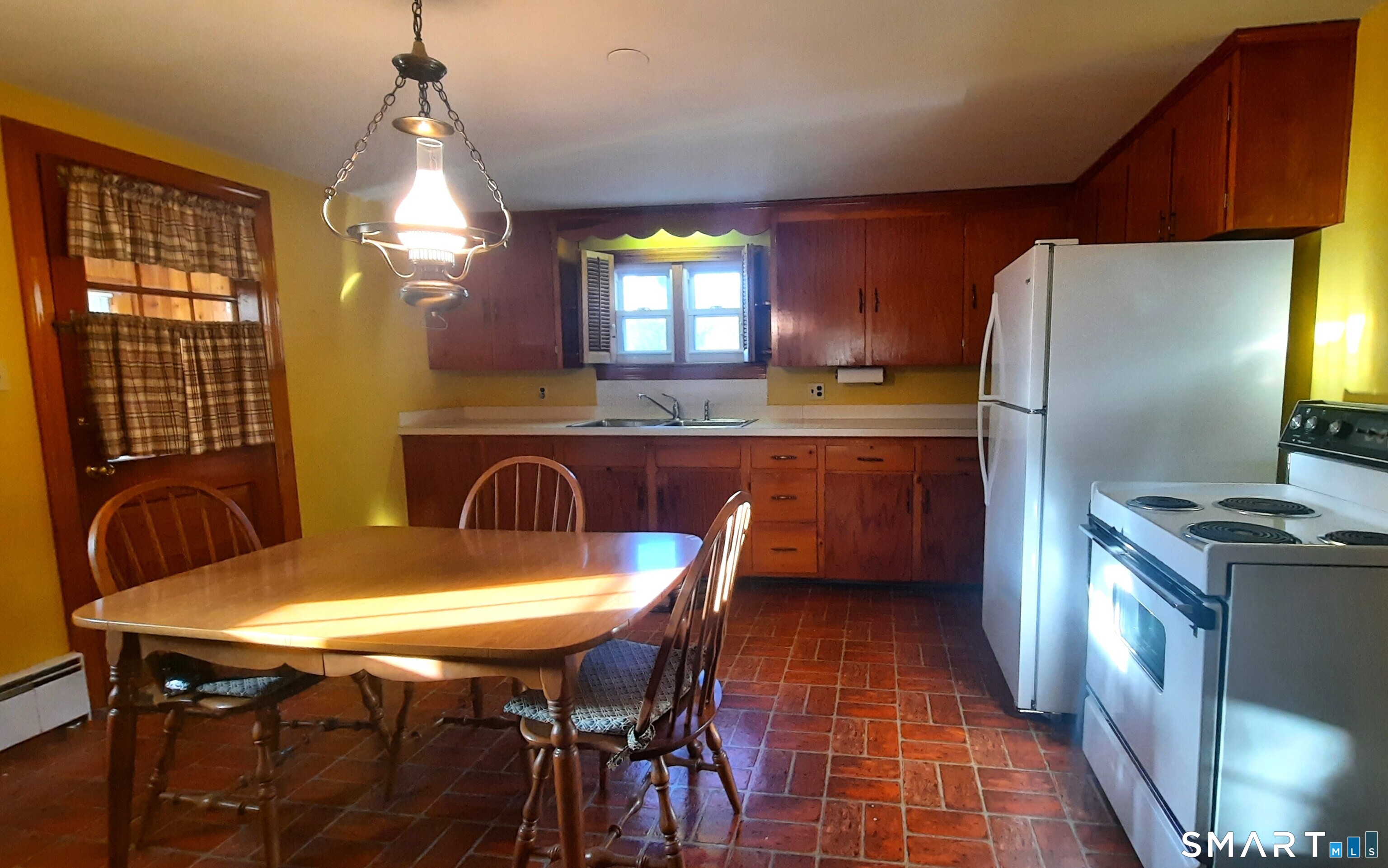 a kitchen with stainless steel appliances granite countertop a sink a stove a refrigerator a dining table and chairs