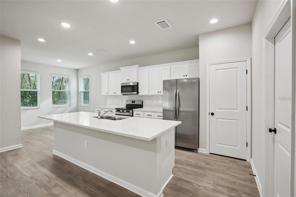 64 Cactus Street Homosassa, FL 34446 - Photo 6 of 12 a kitchen with a refrigerator a sink and white cabinets
