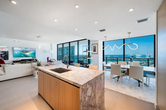 a living room with stainless steel appliances kitchen island furniture and a large window